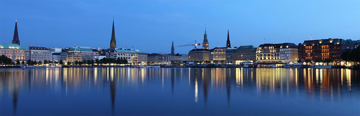 Die Binnenalster in Hamburg zur blauen Stunde, die Uferbebauung spiegelt sich im Wasser